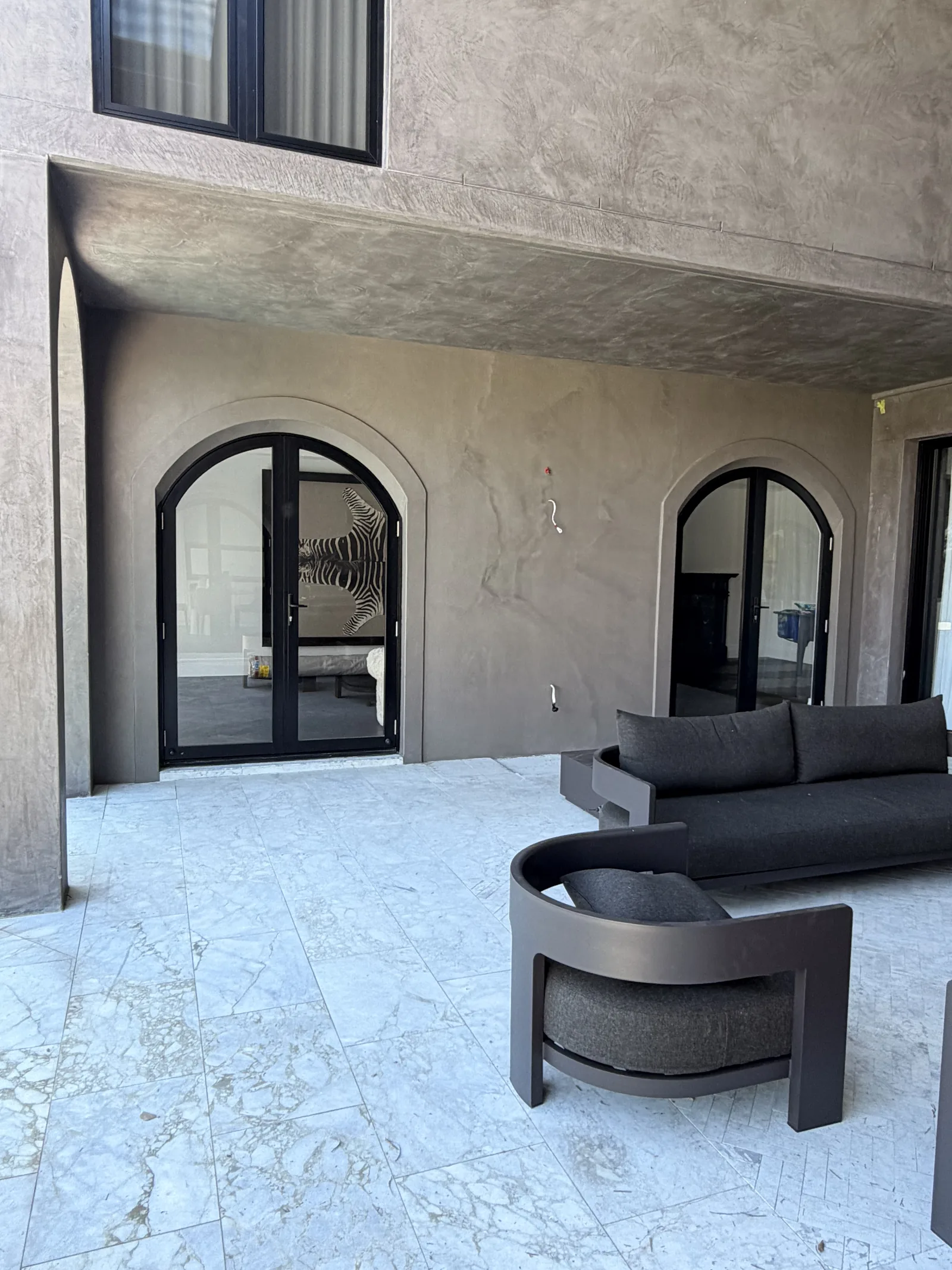 Polished plaster alfresco with arched doors and marble paving