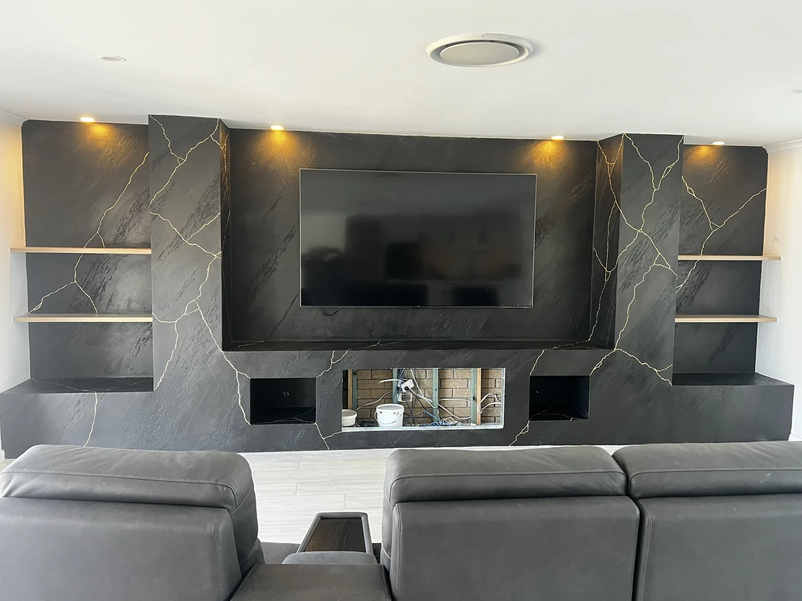 Charcoal marble-effect feature wall with gold veining around a fireplace and television