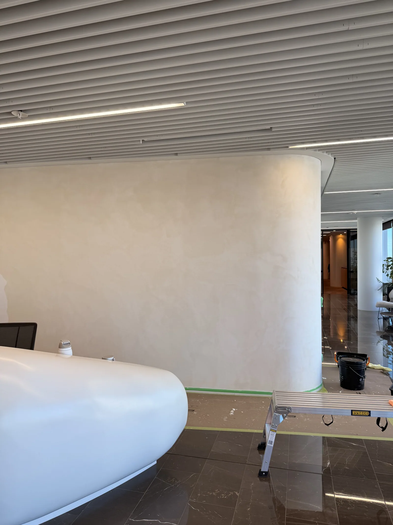 Curved Marmorino wall in cream, with a white office table