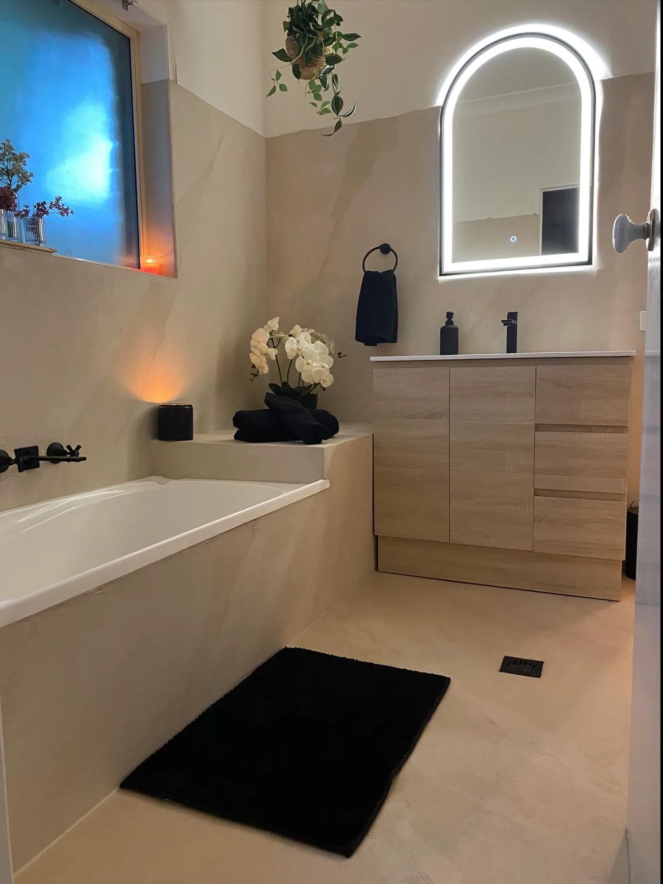 Micro cement bathroom with a built-in bath and an arched mirror