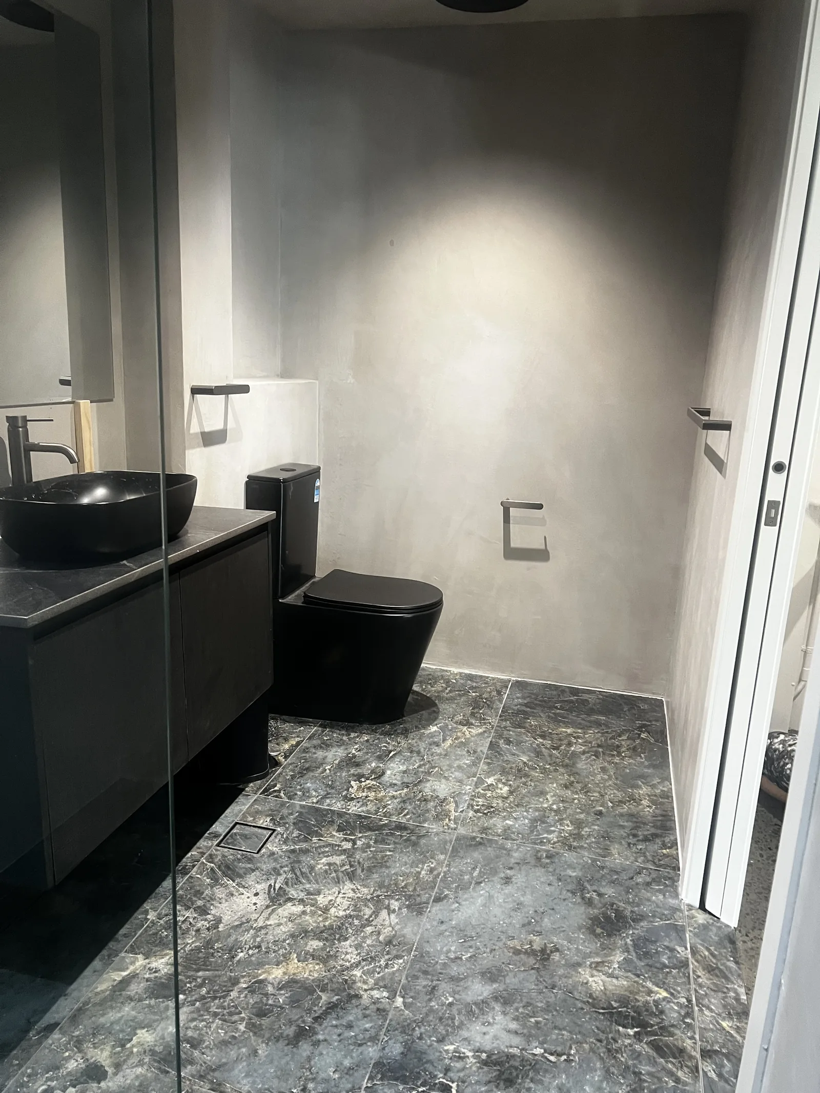 Grey micro cement bathroom with black tapware and marble floor