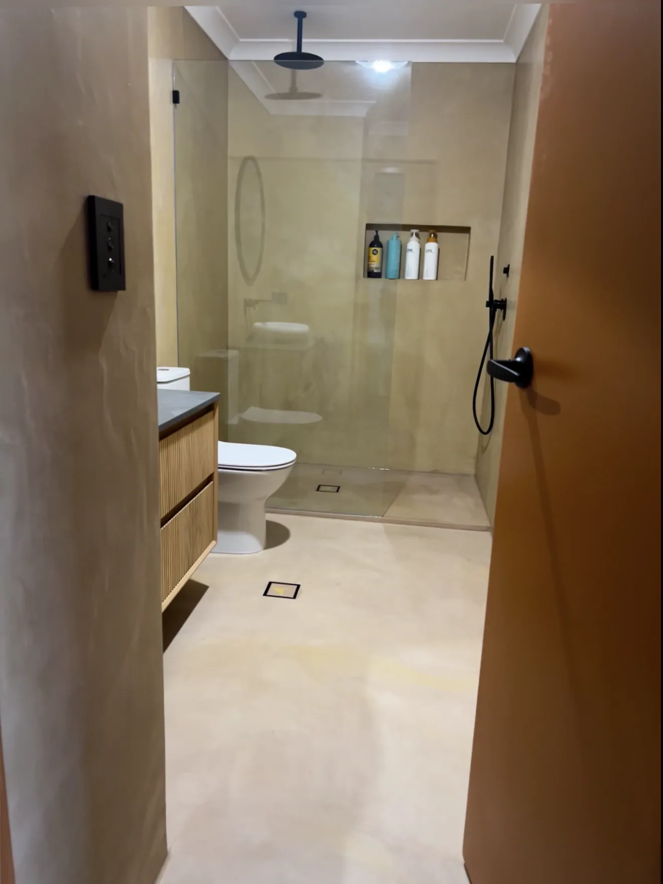 Long micro cement bathroom running through to a walk-in shower