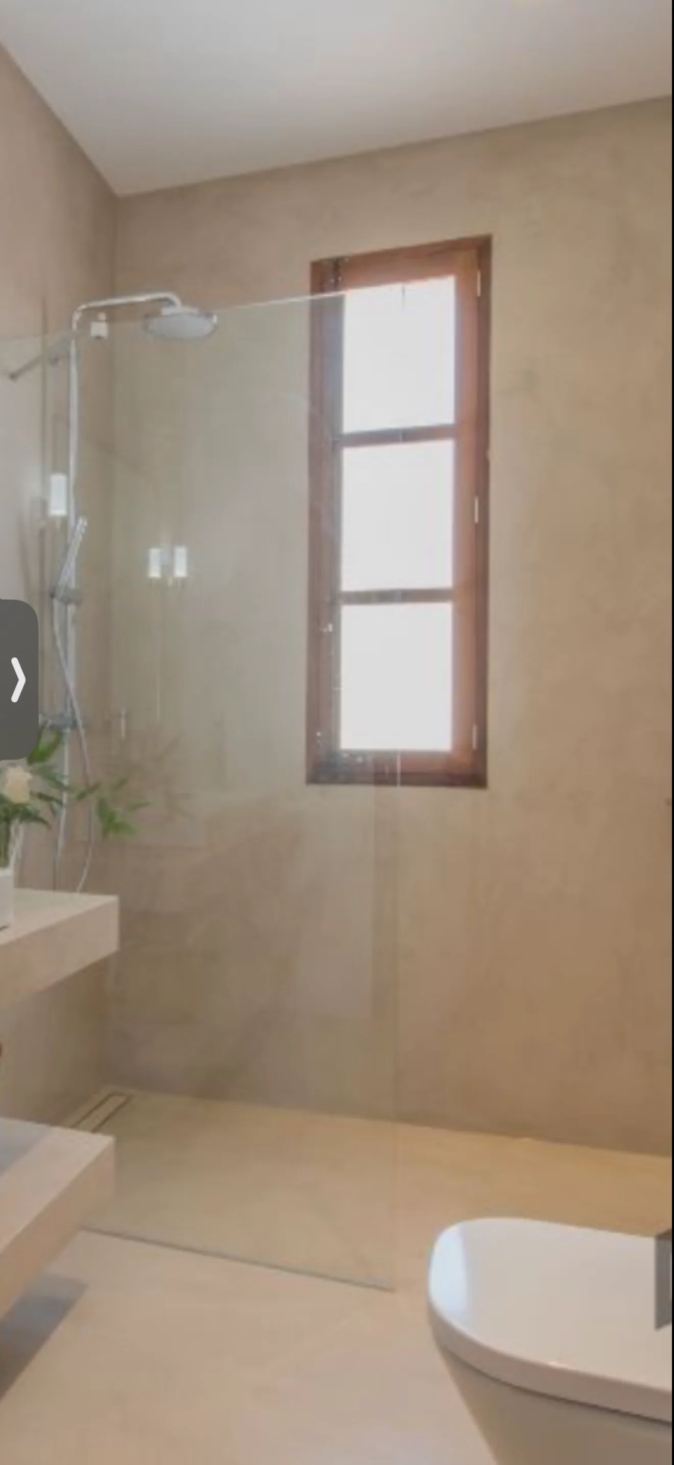 Seamless micro cement bathroom with a walk-in shower and timber-framed window