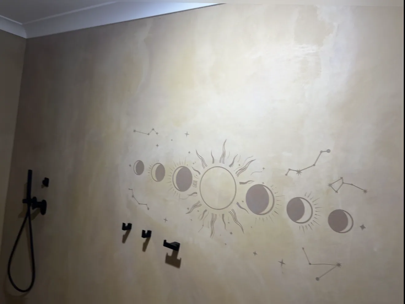 Inverted relief mural of the sun, moon phases and constellations, raised so you can feel it