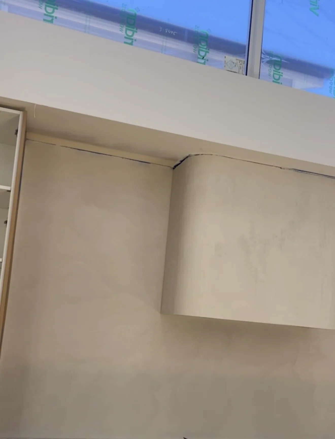 Cream micro cement wall and bulkhead beside a high window