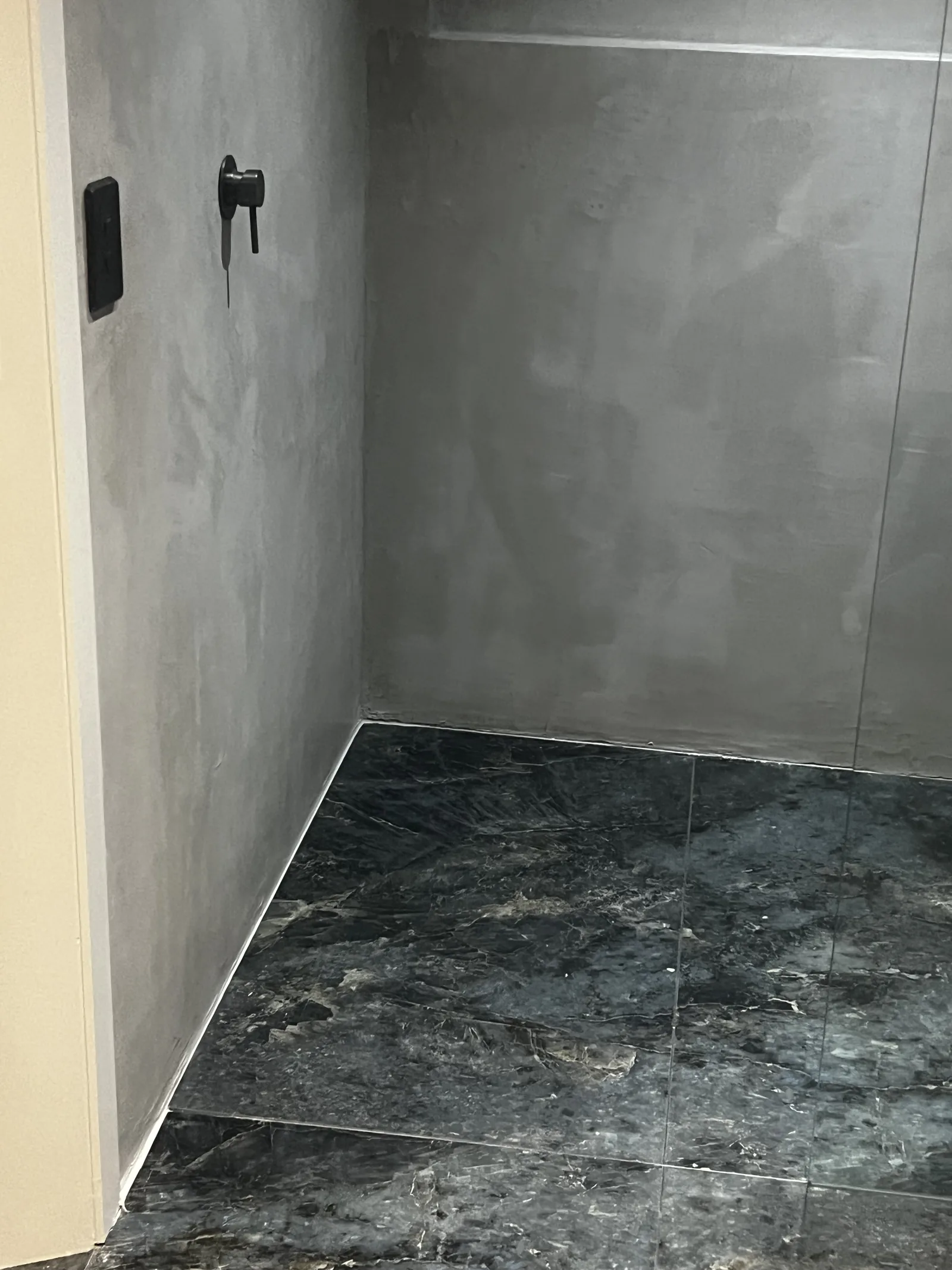 Grey micro cement shower recess with black mixer