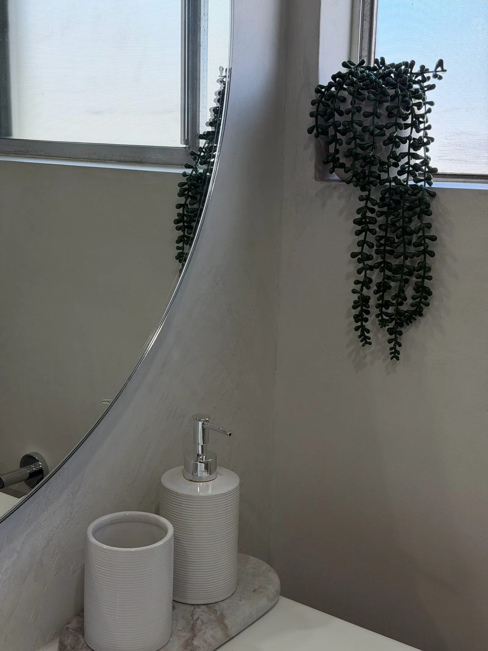 Grey micro cement bathroom corner with a round mirror