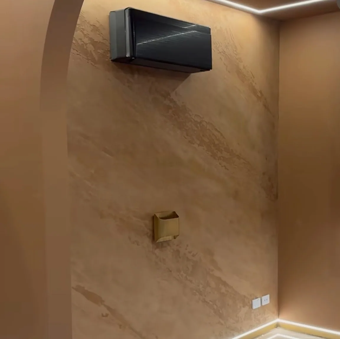 Warm travertine-look room with a plastered arch and concealed cove lighting